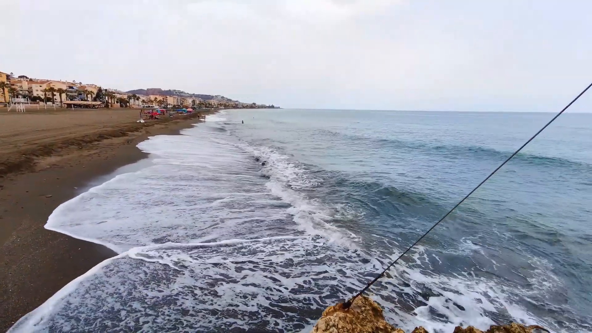 Beach scene with waves and coastal buildings
