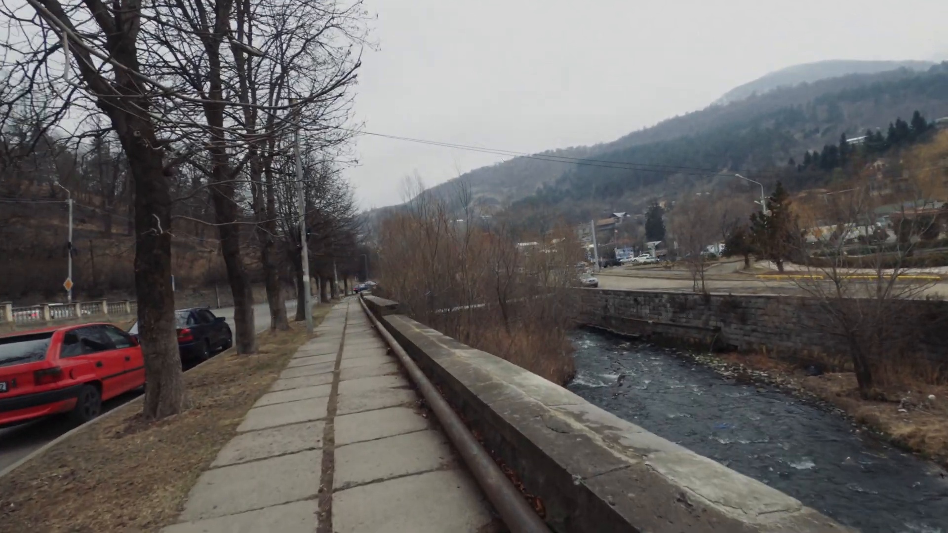 First-person sidewalk beside a river